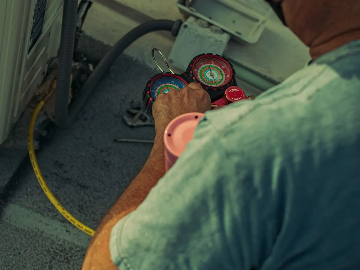 HVAC technician reading refrigerant pressure gauges during an AC tune-up