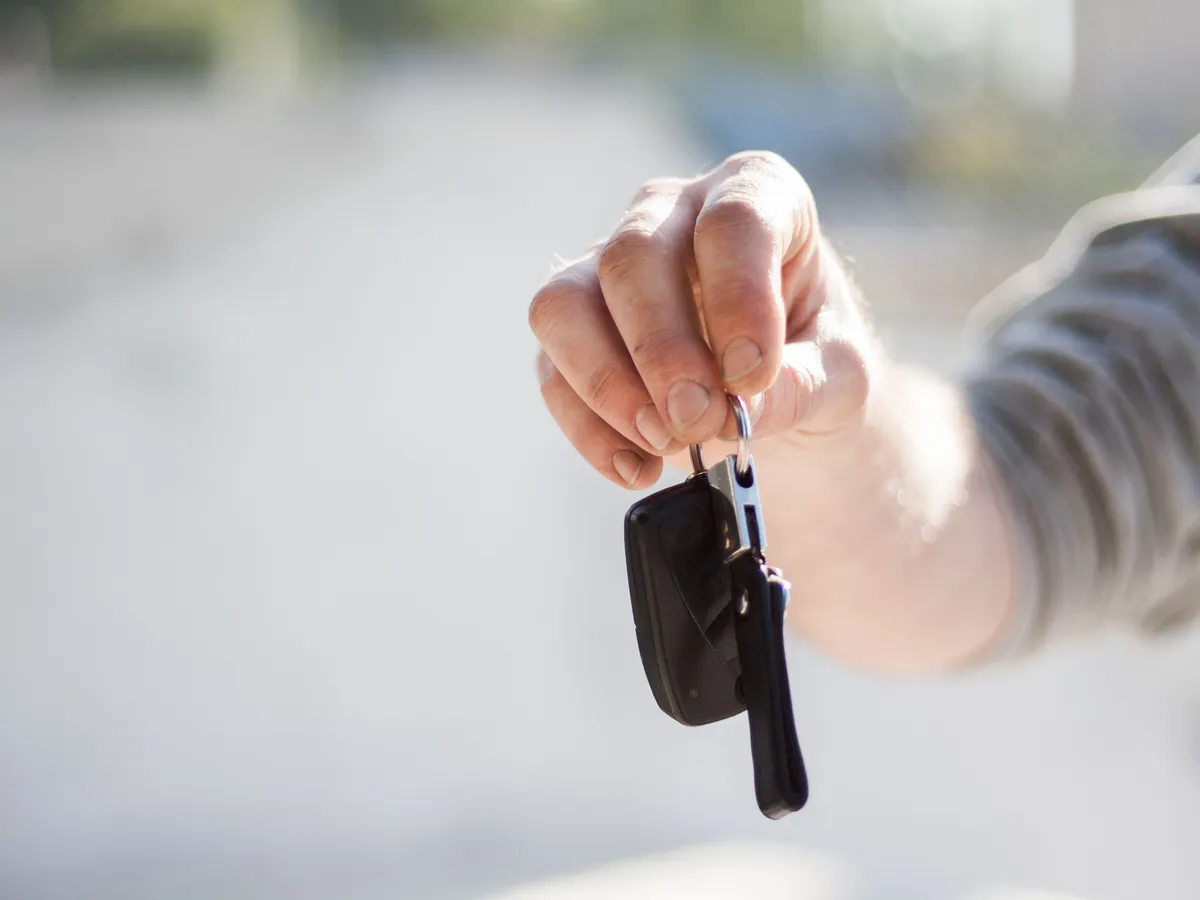 Person handing over car keys after a sale