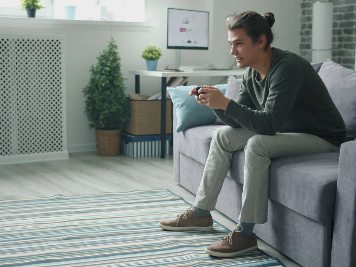 Young man smiling while holding a game controller on a home sofa