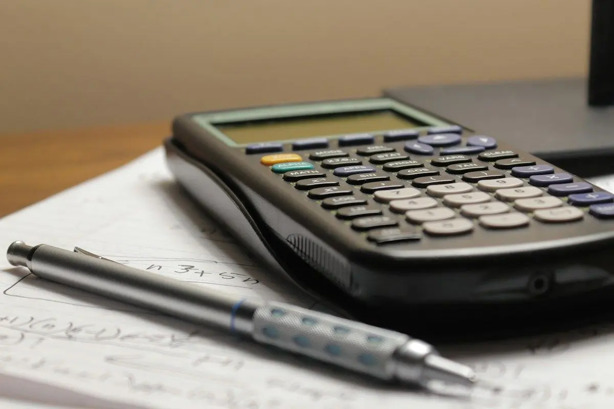 Calculator and pen on printed cost worksheets