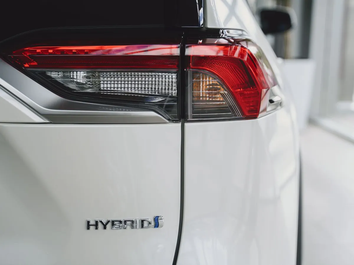 Chrome HYBRID badge below the tail light of a white SUV
