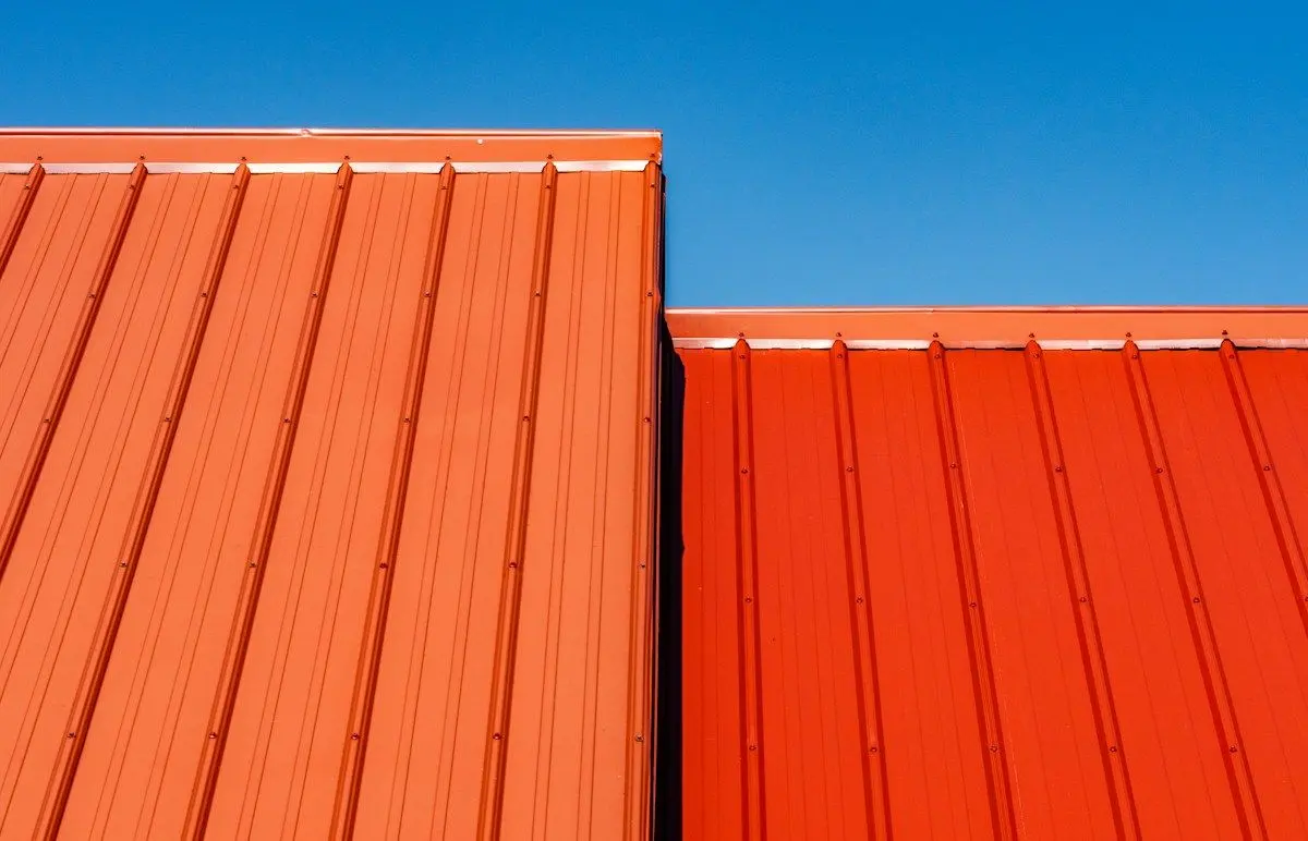 Orange standing-seam metal roof panels against a blue sky