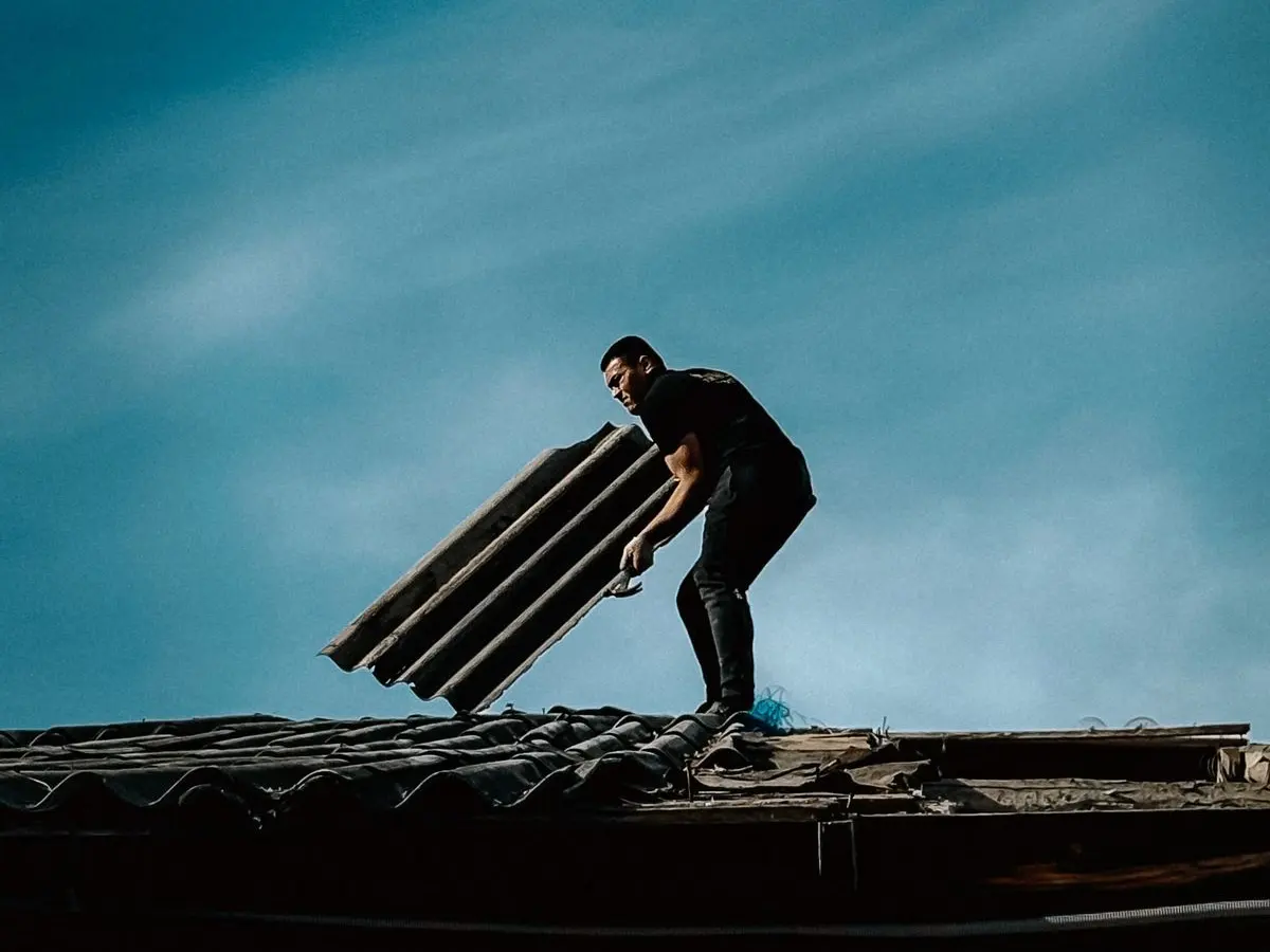 Roofer carrying a bundle of shingles across a roof