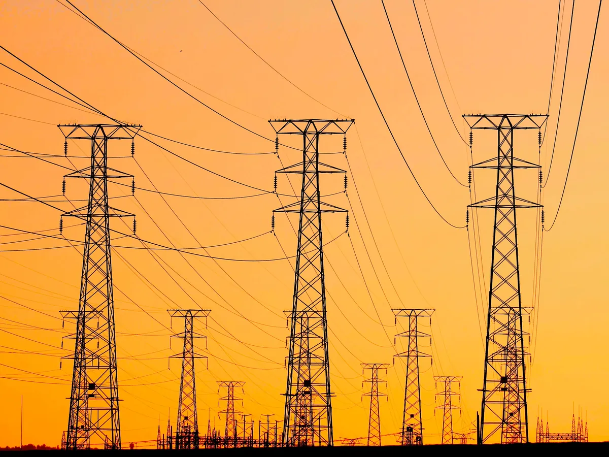 High-voltage transmission towers near houses at dusk