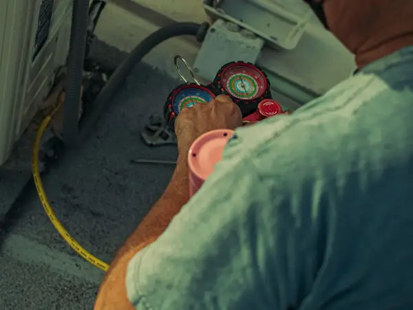 HVAC technician reading refrigerant pressure gauges during an AC tune-up